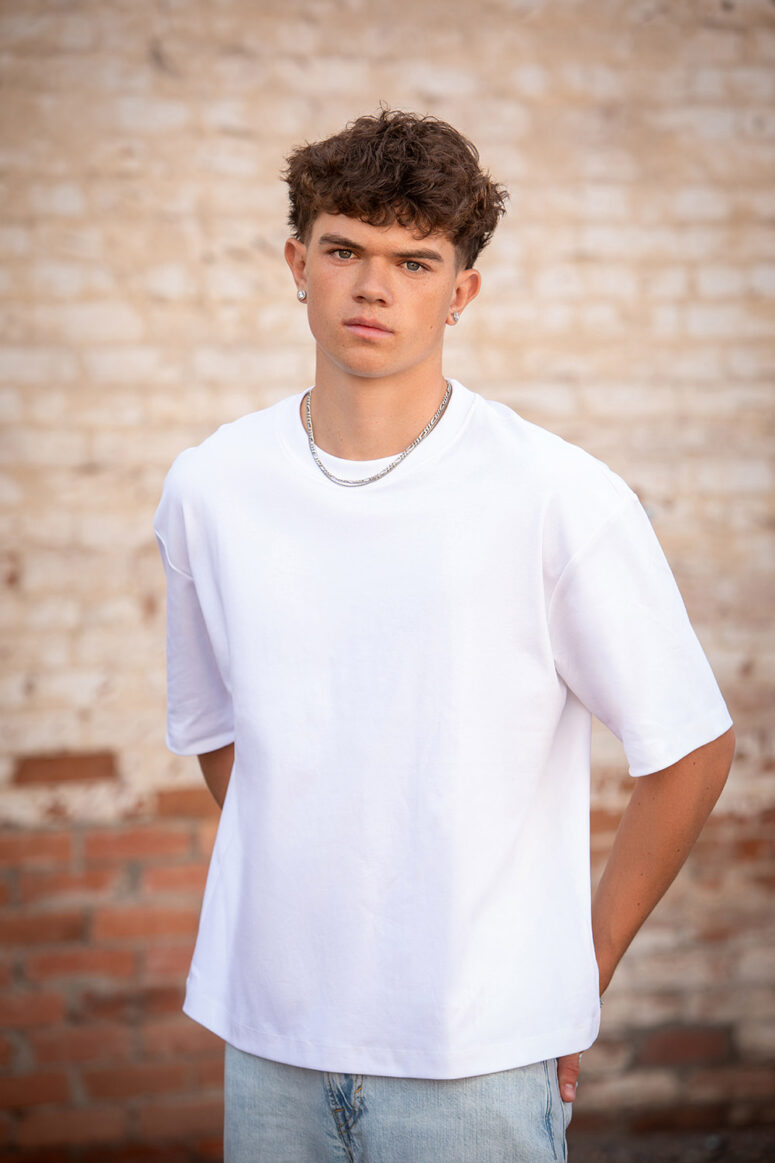 Boy in white against brick wall