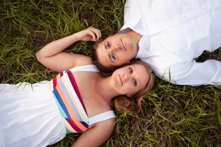 engaged couple lying down in grass