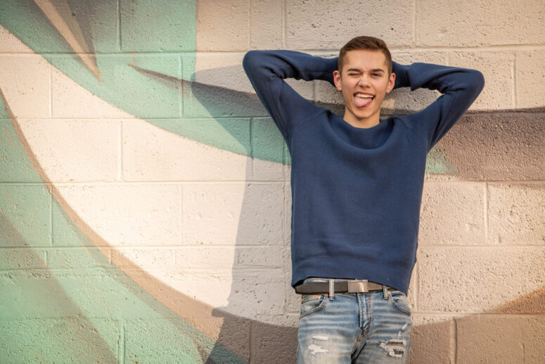 A boy stick his tongue out smiling.