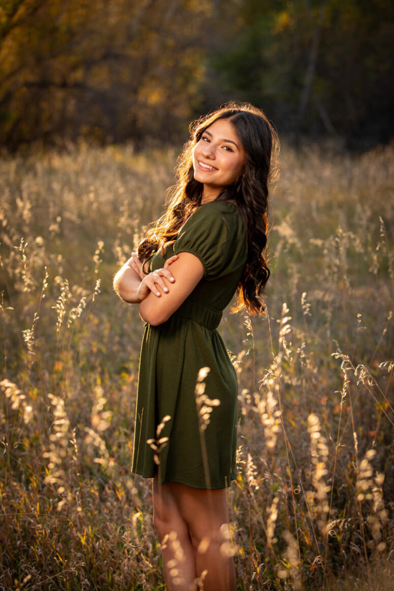 Girl in green dress in sunlit grass field.