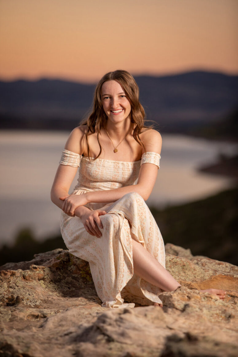 A girl sits on a rock at sunset atop Horsetooth Reservoir.
