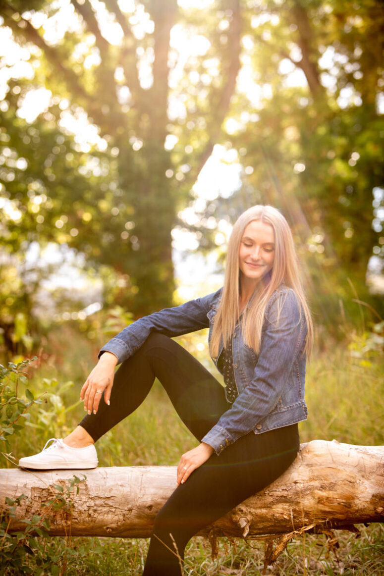 Sun comes through tree illuminating girl in jean jacket.