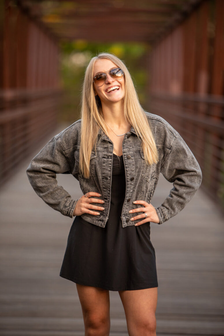 High school senior portrait of girl in jean jacket and sunglasses.