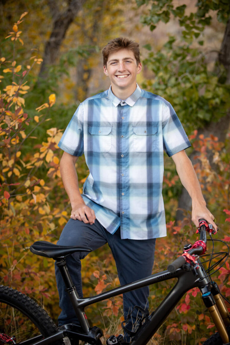 A portrait of a student smiling with his mountain bike.