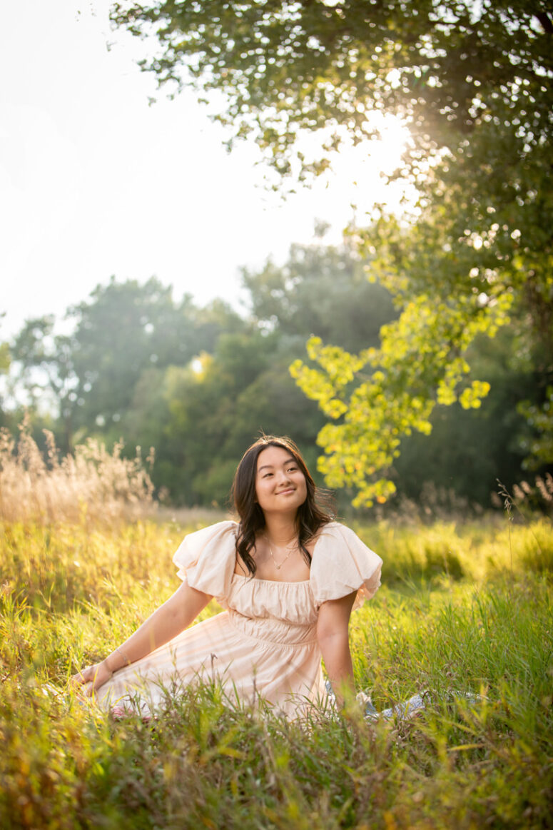 A girls in a green field at sunset.