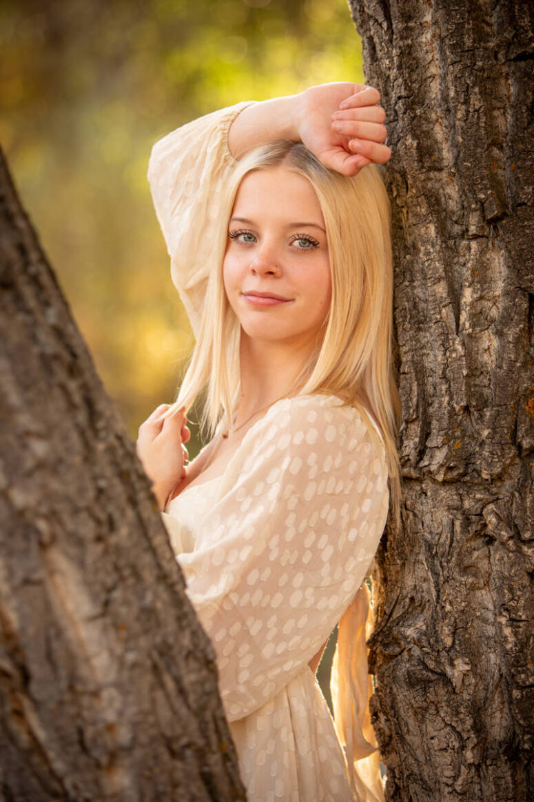 A girl in white nestled amongst trees.